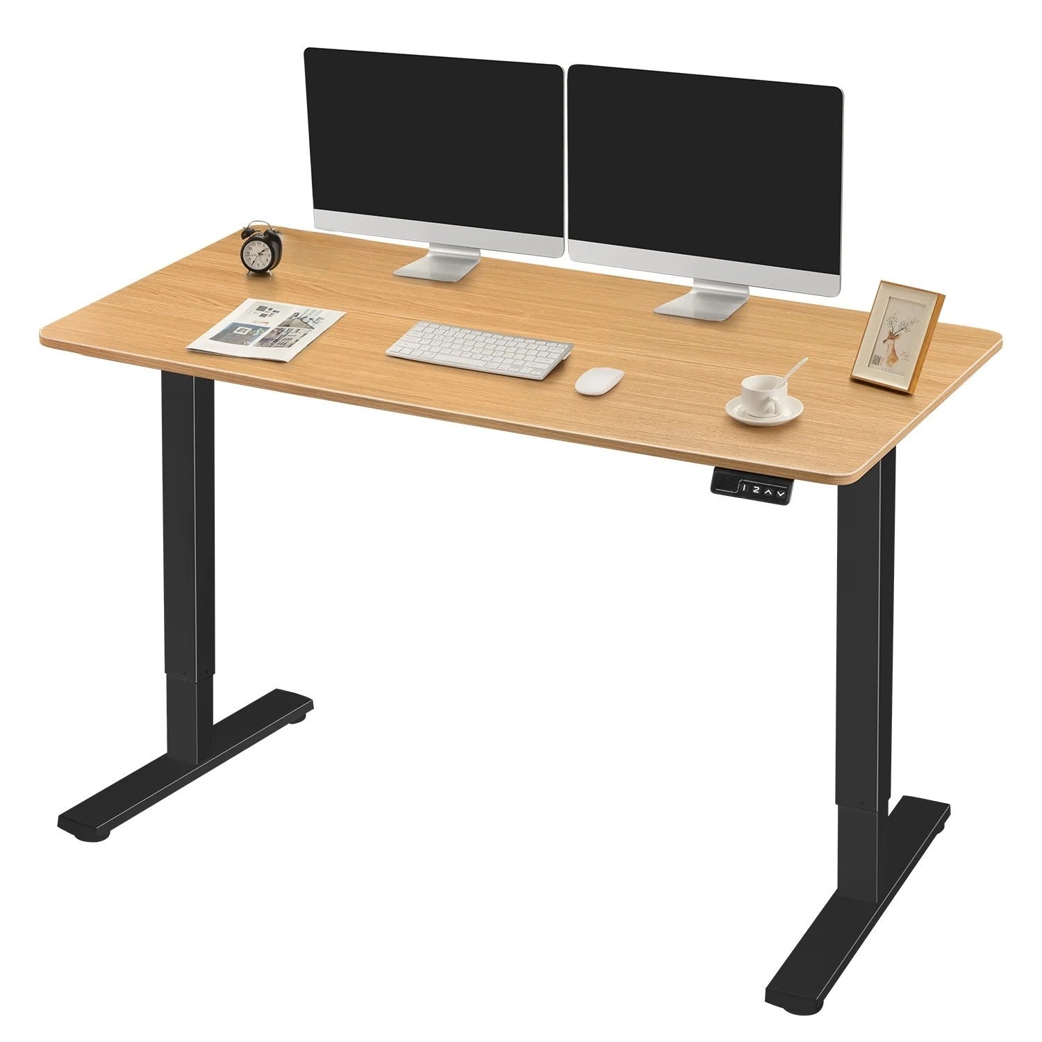 The Refurne Electric Height Adjustable Stand-Up Desk, featuring a beige tabletop and black frame, displays two monitors, keyboard, mouse, cup and saucer, alarm clock, framed photo, and neatly arranged papers on its surface.