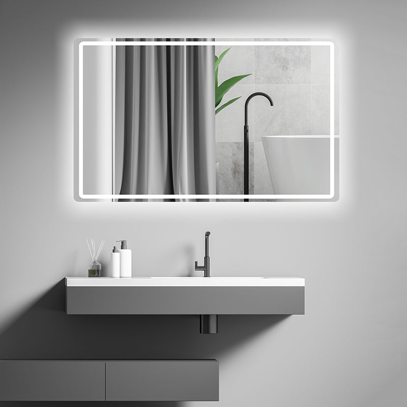 A modern bathroom featuring a floating sink, a Refurne Smart LED Bathroom Mirror with defogging and adjustable lighting, a gray curtain, white bathtub, plant leaves, and minimal toiletries on the countertop.