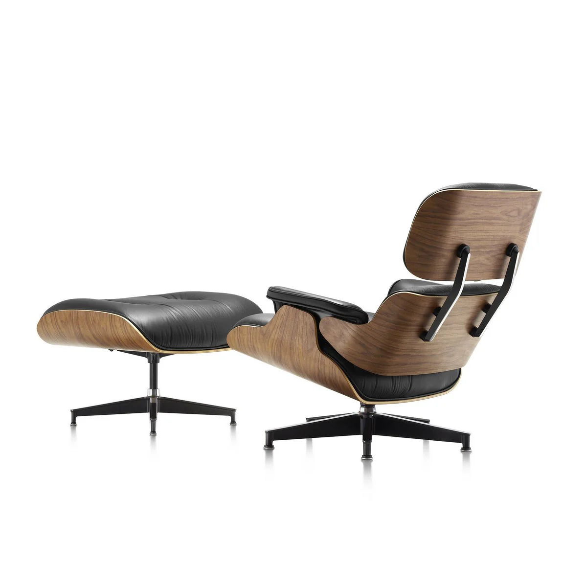 The Refurne Eames Style Lounge Chair & Ottoman features walnut wood colour, black leather cushions, and curved frames with black metal legs—seen from the rear on a white background. Brand new.