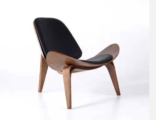 The Refurne CH07 Shell Lounge Chair in walnut and black leather, inspired by Hans Wengers iconic mid-century modern design, features a curved wooden frame and upholstery, shown against a plain white background.