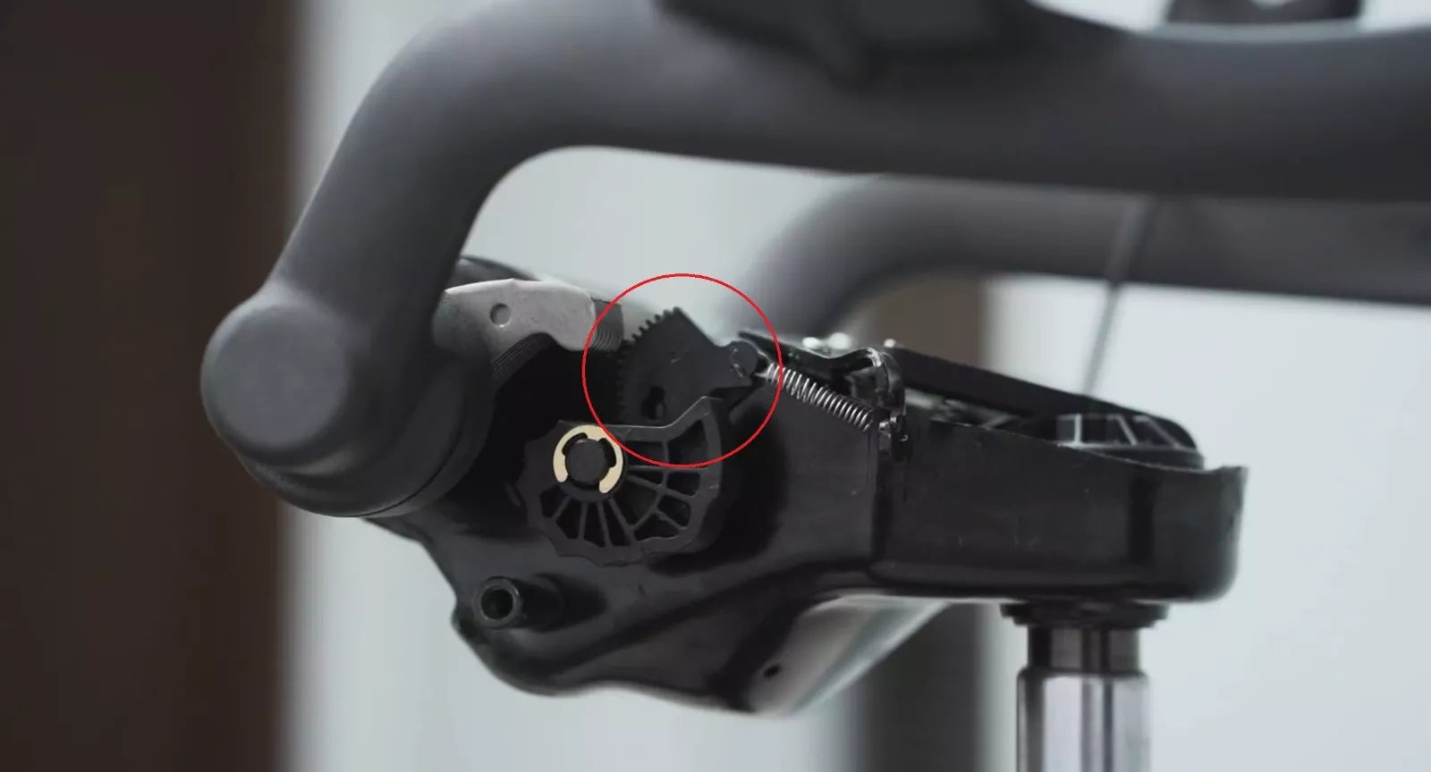 Close-up of a bicycle shifter mechanism with a red circle highlighting an internal gear, similar to the Refurne Tilt Limiter Sector Gear for Classic Herman Miller Aeron Chair (MK1 & MK2), among other mechanical parts and levers.