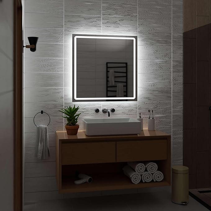 A modern bathroom featuring the Refurne Smart LED Bathroom Mirror – Square (White Light, Defogging, Frameless) above a rectangular sink on a wooden vanity, with plants, toiletries, rolled towels below, and a towel ring nearby.