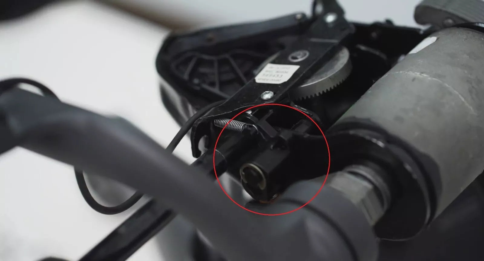 Close-up of the Forward Tilt Cam for Classic Herman Miller Aeron Chair (MK1 & MK2) by Refurne, an essential replacement part, circled in red among gears and a spring against a blurred background.